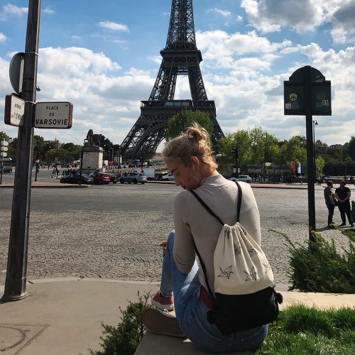 Young girl with drawstring bag in front of eiffel tower
